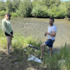 Man and woman installing water quality sensor on the bank of a river