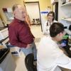 Professor Karl Linden laughing with students in a lab. 