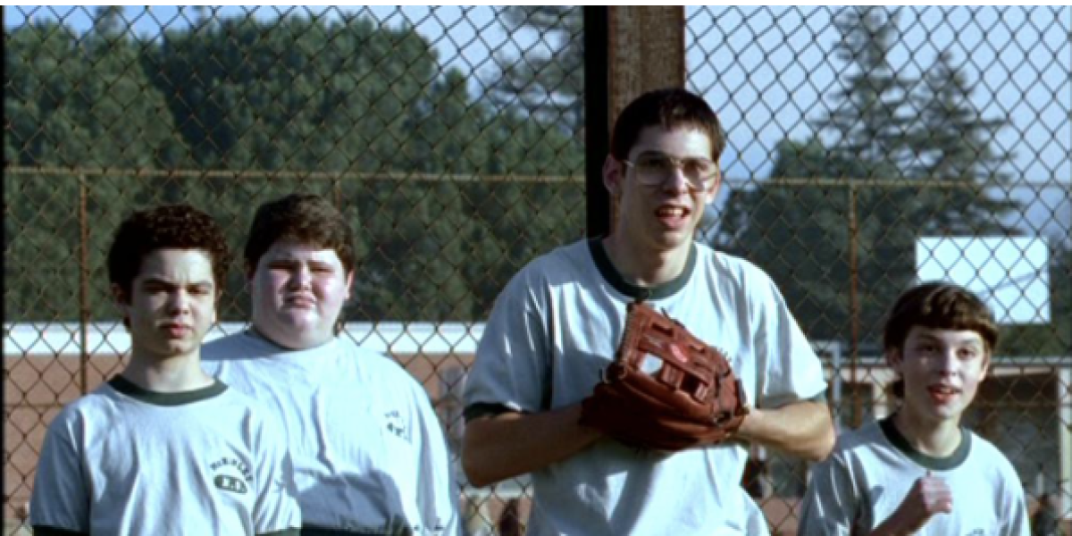 kids playing baseball standing next to fence
