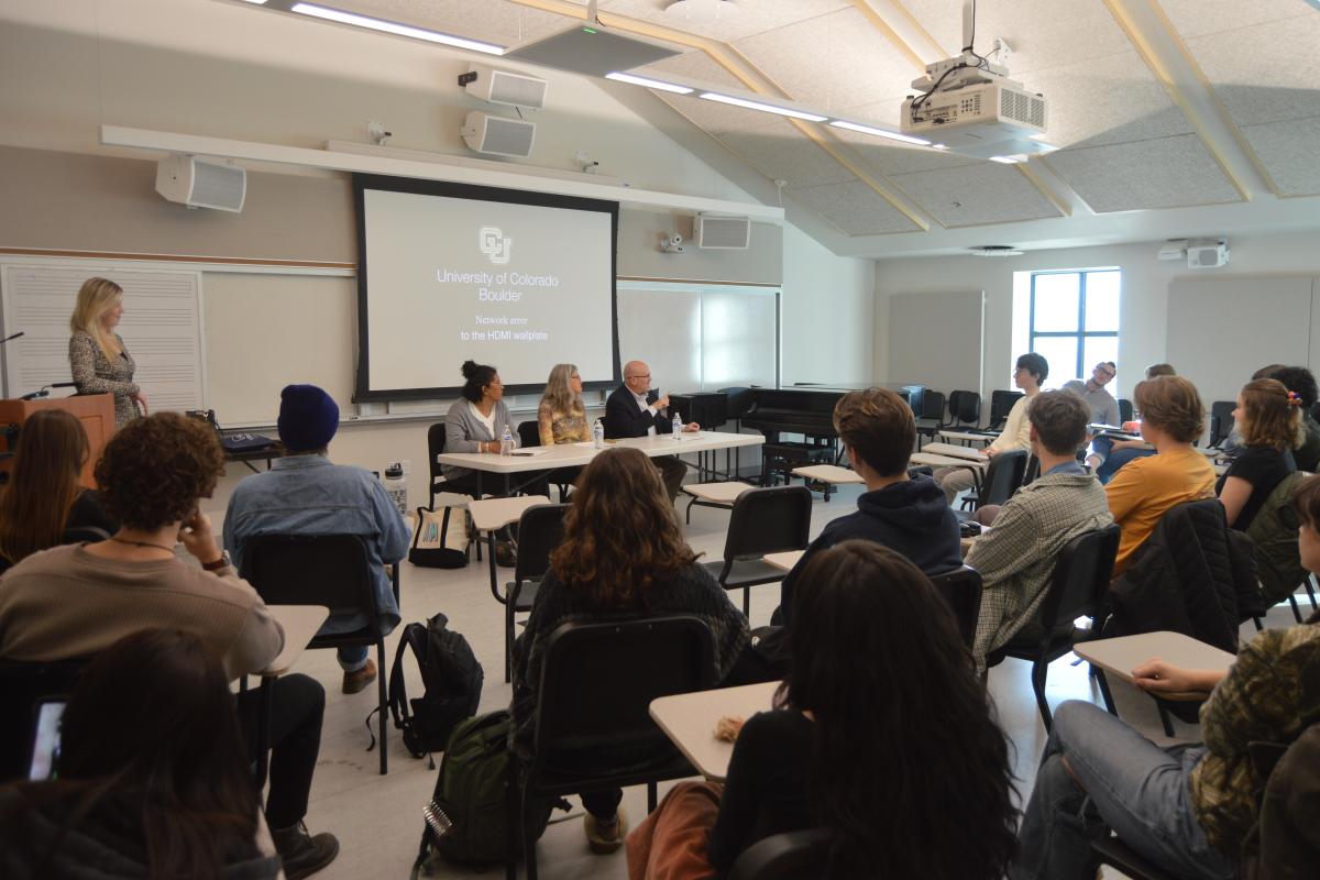 A classroom full of people with a panel up front