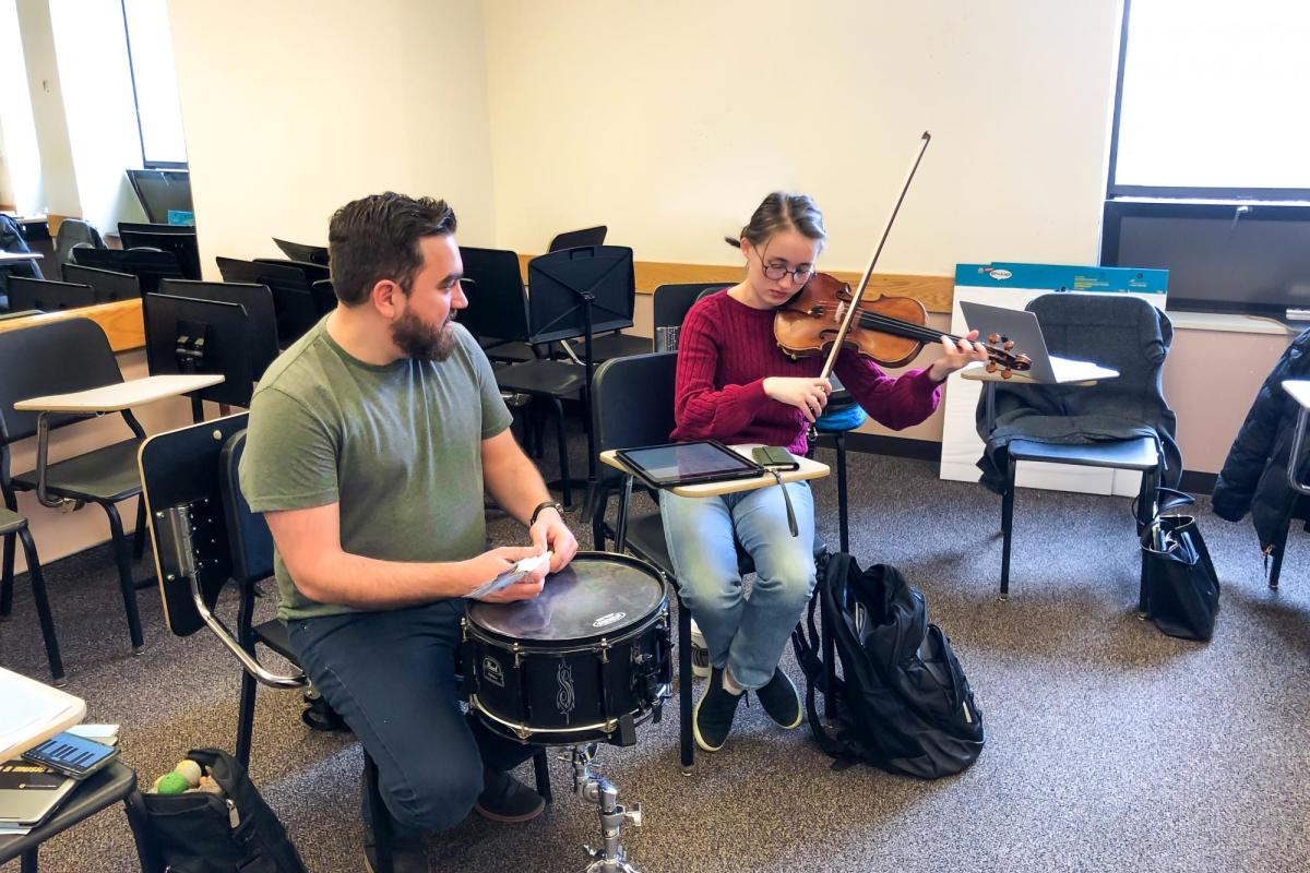 two musicians playing music, violin & percussion