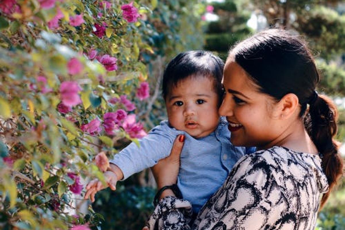 infant and mother by flower bush