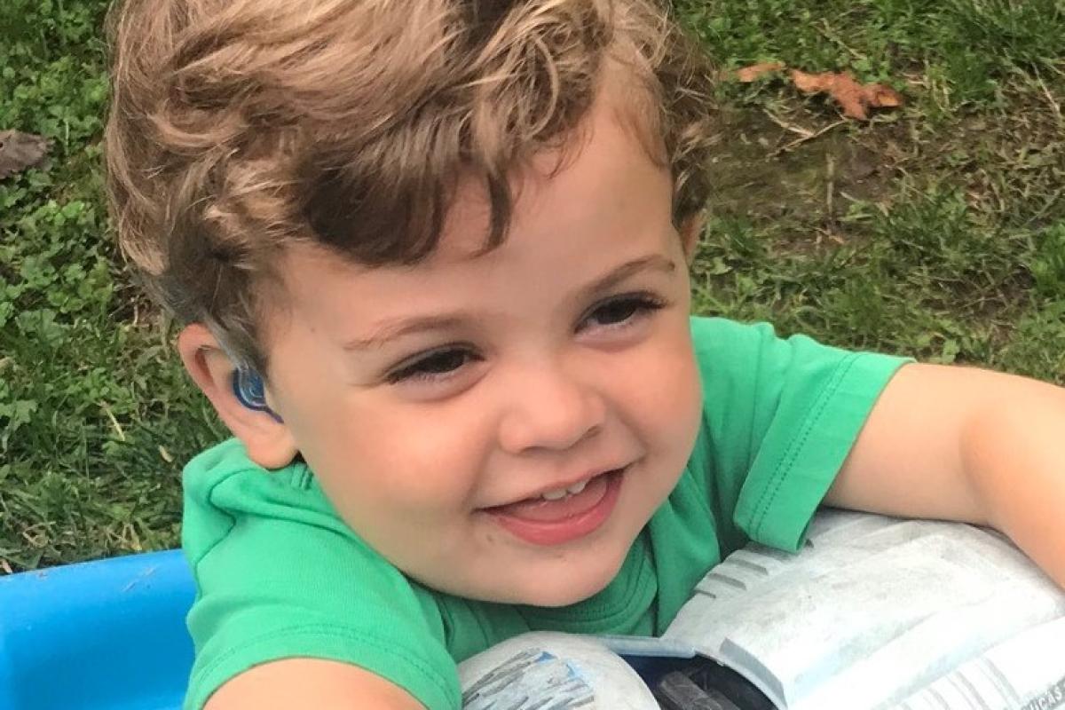 toddler with hearing aid holding truck