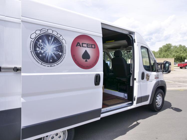 mobile lab parked with door open and Cosmic and Aced study logos