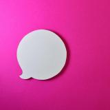 white paper chat bubble on a surface with a pink background