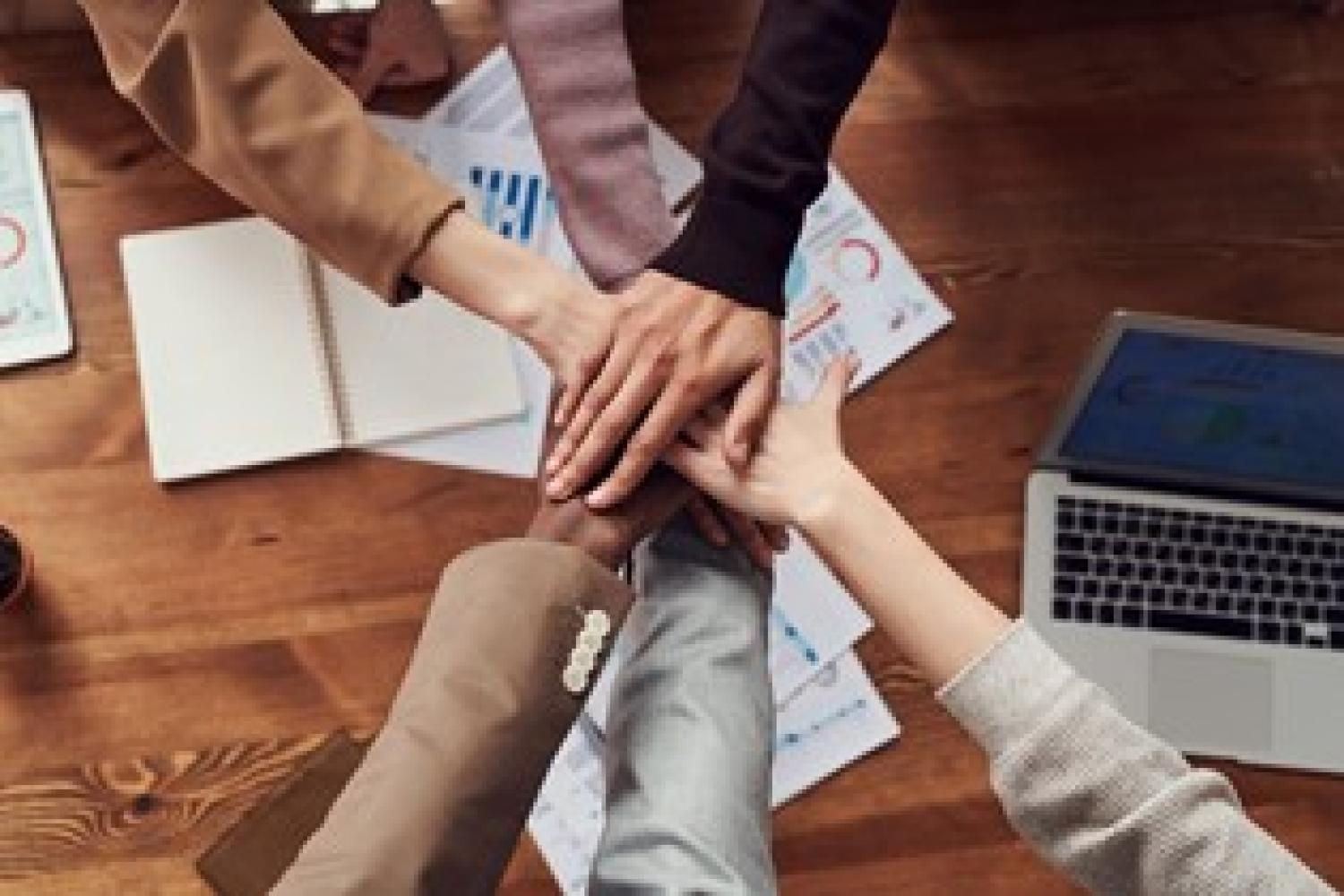 people in an office join hands in a circle