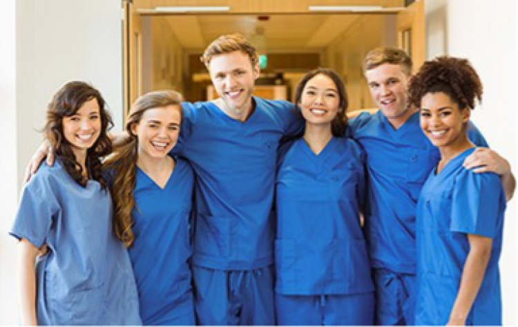 A group of people stand in scrubs smiling