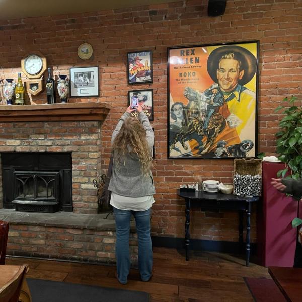 Tamar McKee with the Center of the American West takes a photo of Zane Grey film posters on display at the Weatherford Hotel.