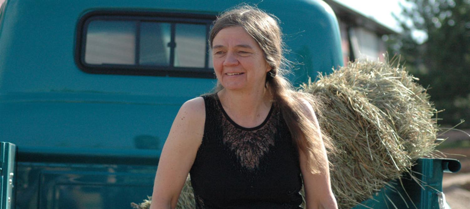 Patty Limerick smiling next to haystack