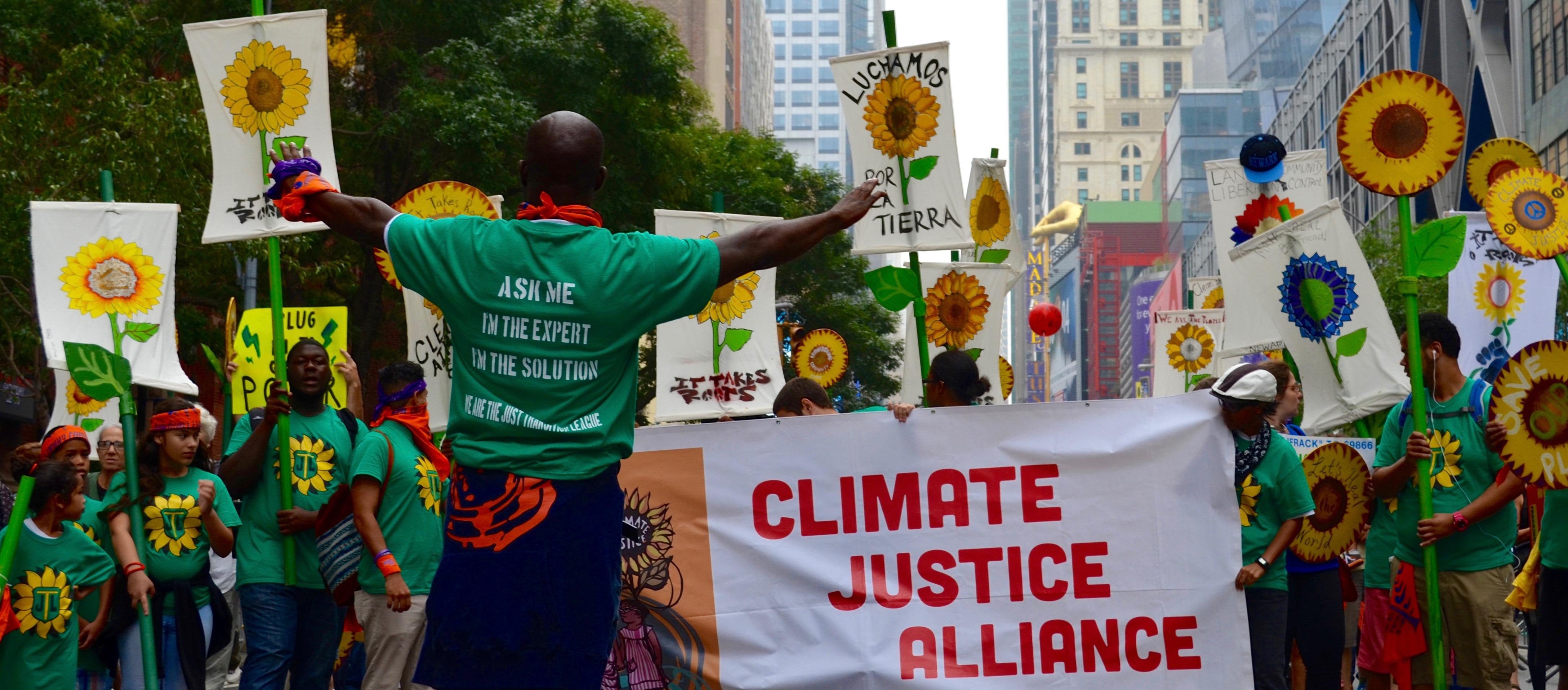 A group marches in the Peoples Climate March holding a banner "Climate Justice Alliance"