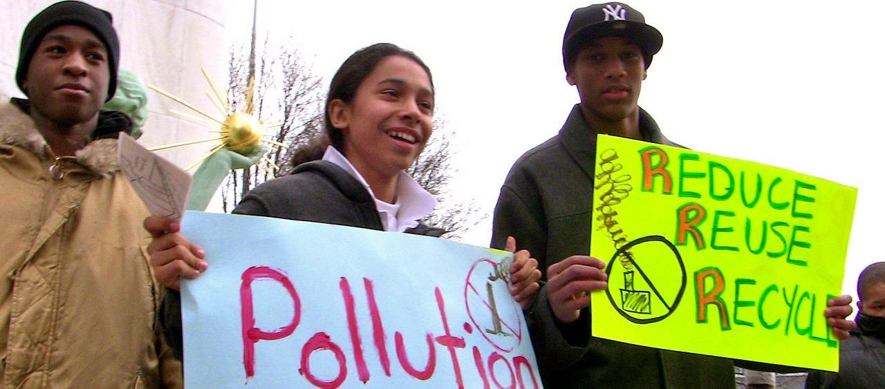 Three youth holds signs at a demonstration against a waste incinerator in Detroit