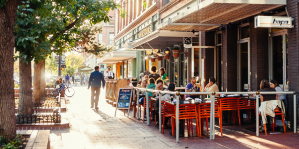 A picture of a man walking by a restaurant on Pearl Street in Boulder, CO