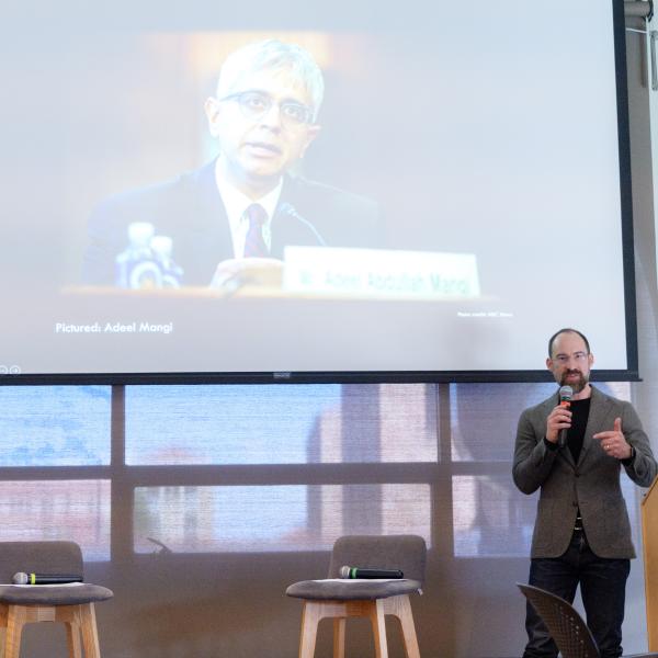 Caleb Elfenbein holding a microphone while presenting his work