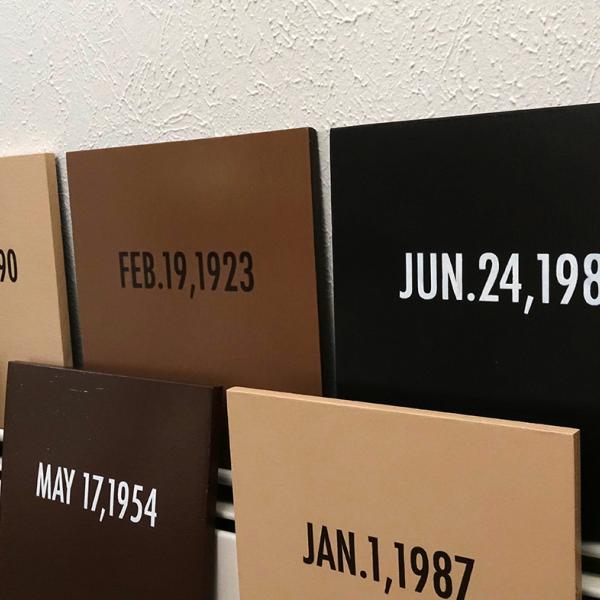 Wooden plaques painted in various shades of skin tones contain dates and QR codes