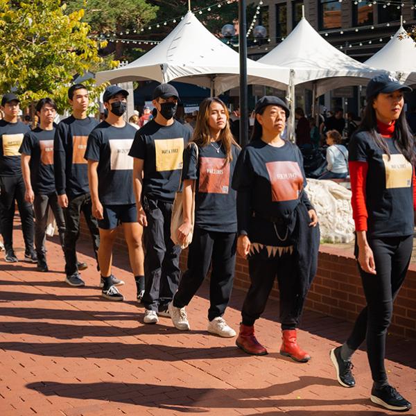 Close up image from political art performance in the form of a silent procession through downtown Boulder that took place in October 2022. Each person is wearing a shirt with a skin-toned color square that represents a court case date that traces events that laid the foundation of xenophobic and racist opinions and actions against Asians, Asian Americans and Pacific Islanders living in America.