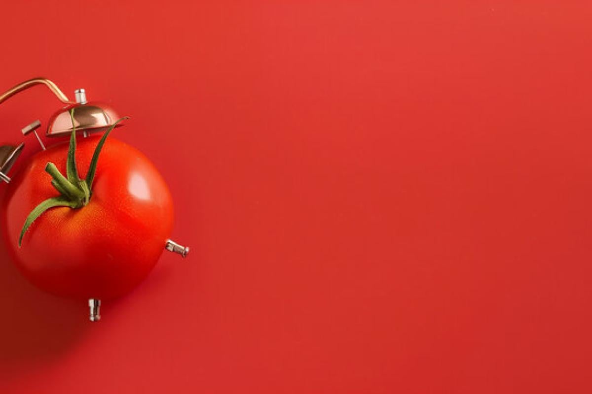 Red tomato visualized as alarm clock with red background