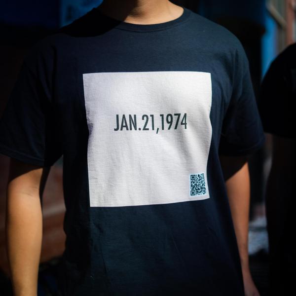 Skin-toned square on black t-shirt with date, "January 21, 1974" shown. This date represents the date that under the Civil Rights Act of 1964, a California school district receiving federal funds must provide non-English-speaking students with instruction in the English language to ensure that they receive an equal education.