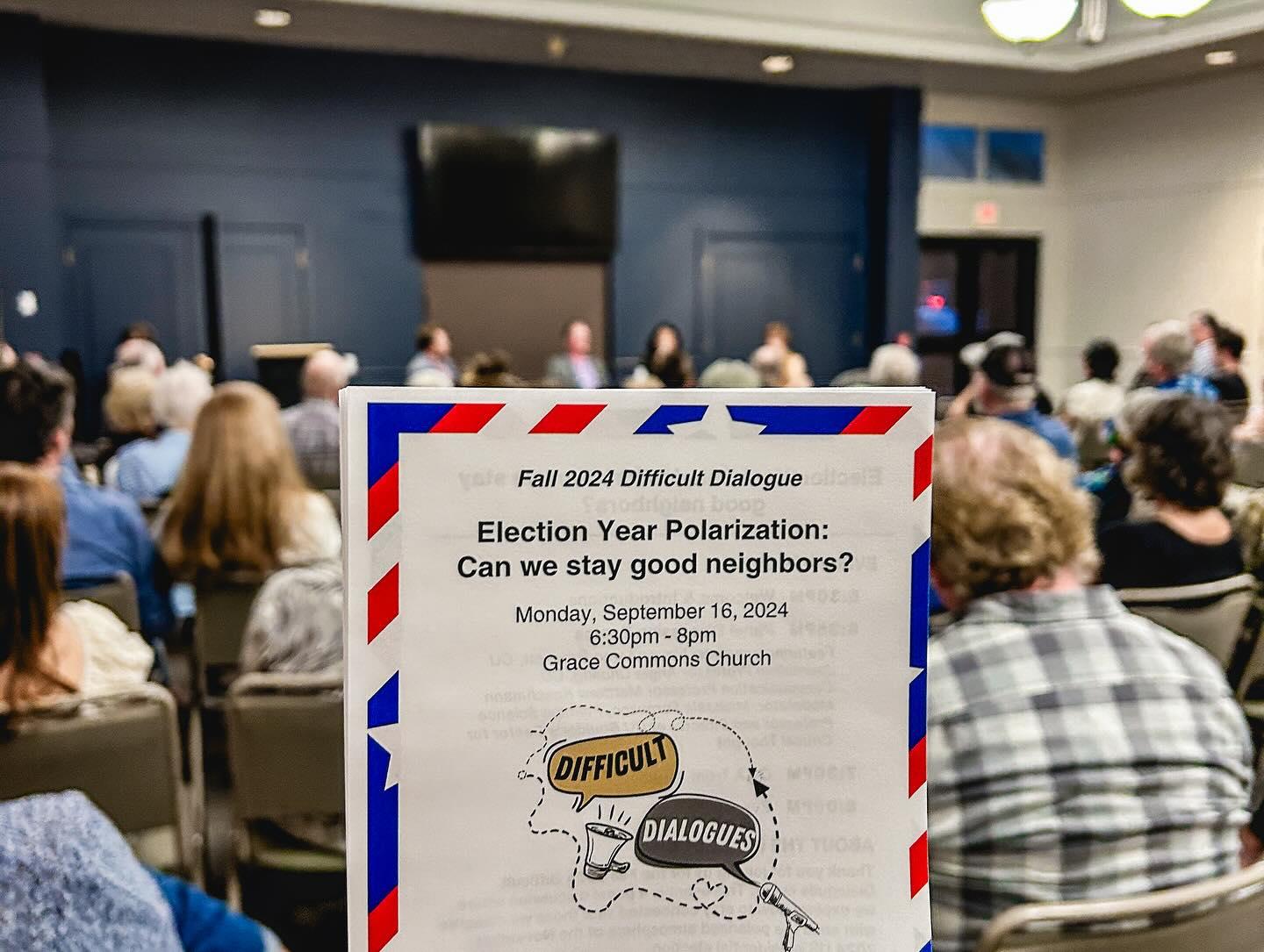 Image of a printed flyer that reads "Fall 2024 Difficult Dialogue - Election Year Polarization: Can we stay good neighbors?" with a graphic text bubble that reads "Difficult" on the left side and "Dialogues" on the right. Background is a blurred audience sitting down, facing away from the camera.