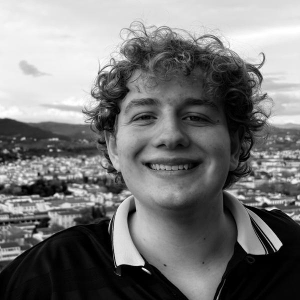 Closeup of Aidan Magruder with a view of a town below and the sky.