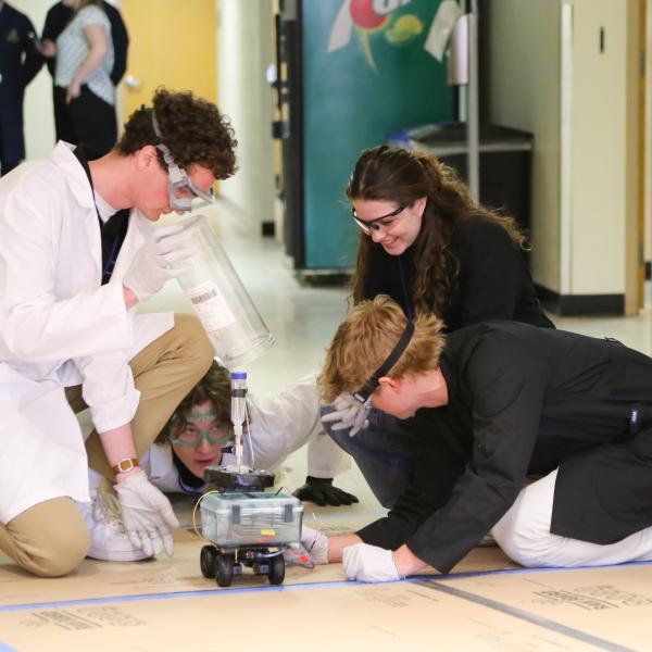 CU Boulder students bend over their car at the AIChE competition