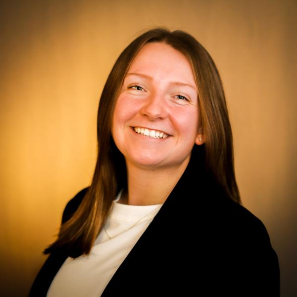 Delaney McNally in a dark blazer against a tan background