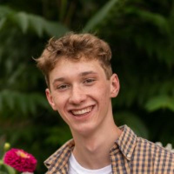 Jackson Carter in an open button-down shirt and a t-shirt underneath it.