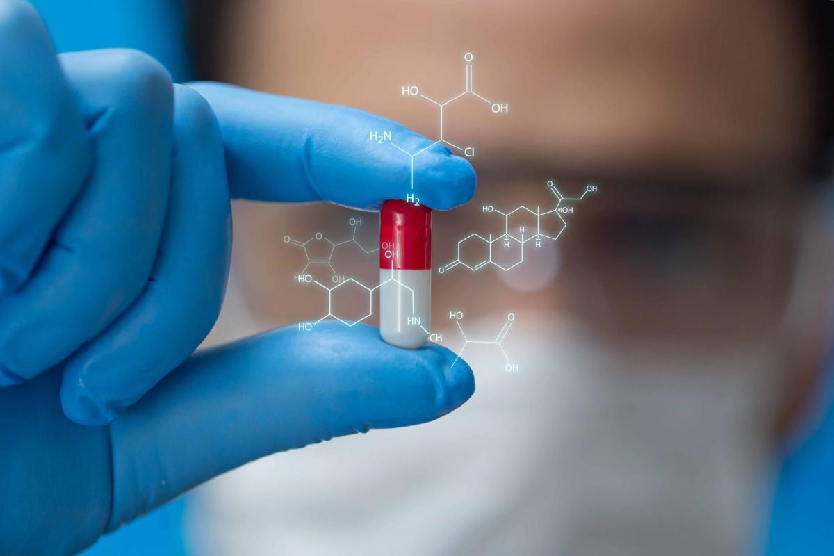 Scientist in lab holding a pill with chemical structure superimposed