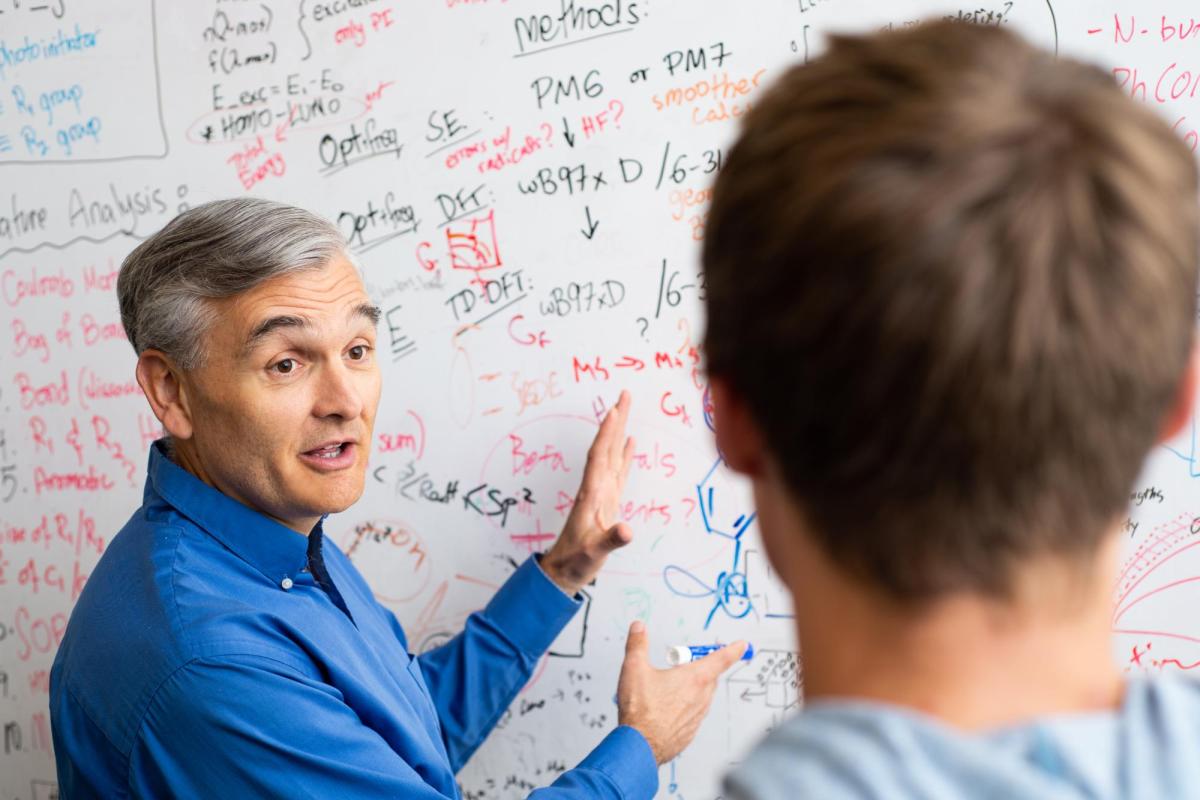 Charles Musgrave discusses some notes on a whiteboard with a student