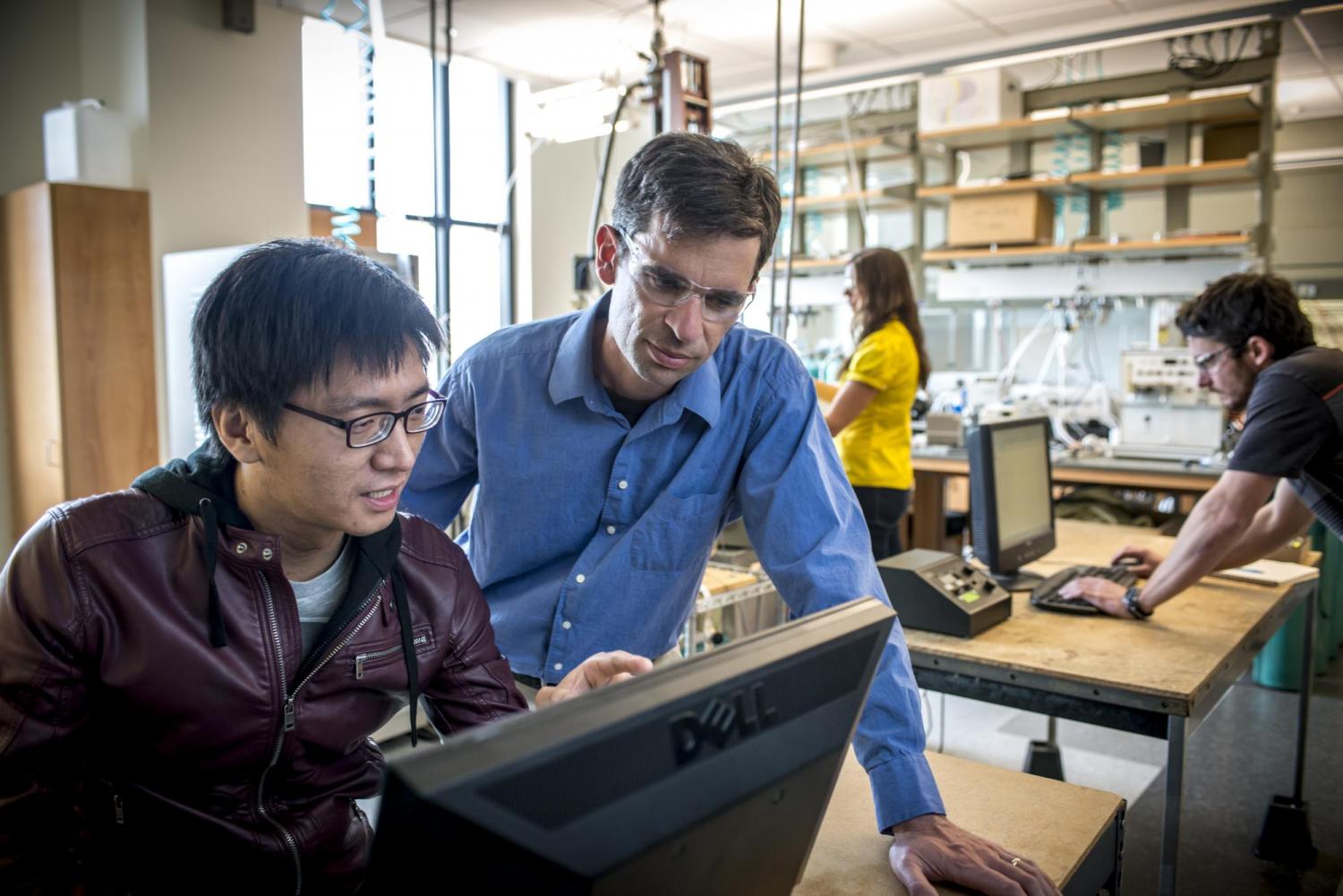 Professor Will Medlin works at a computer with a graduate student.