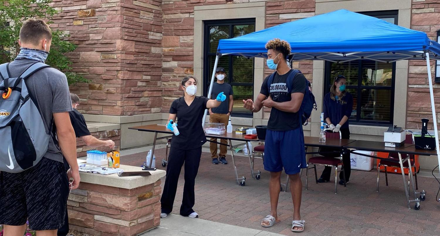 Volunteers test students at a collection station outside of the Athletics Department