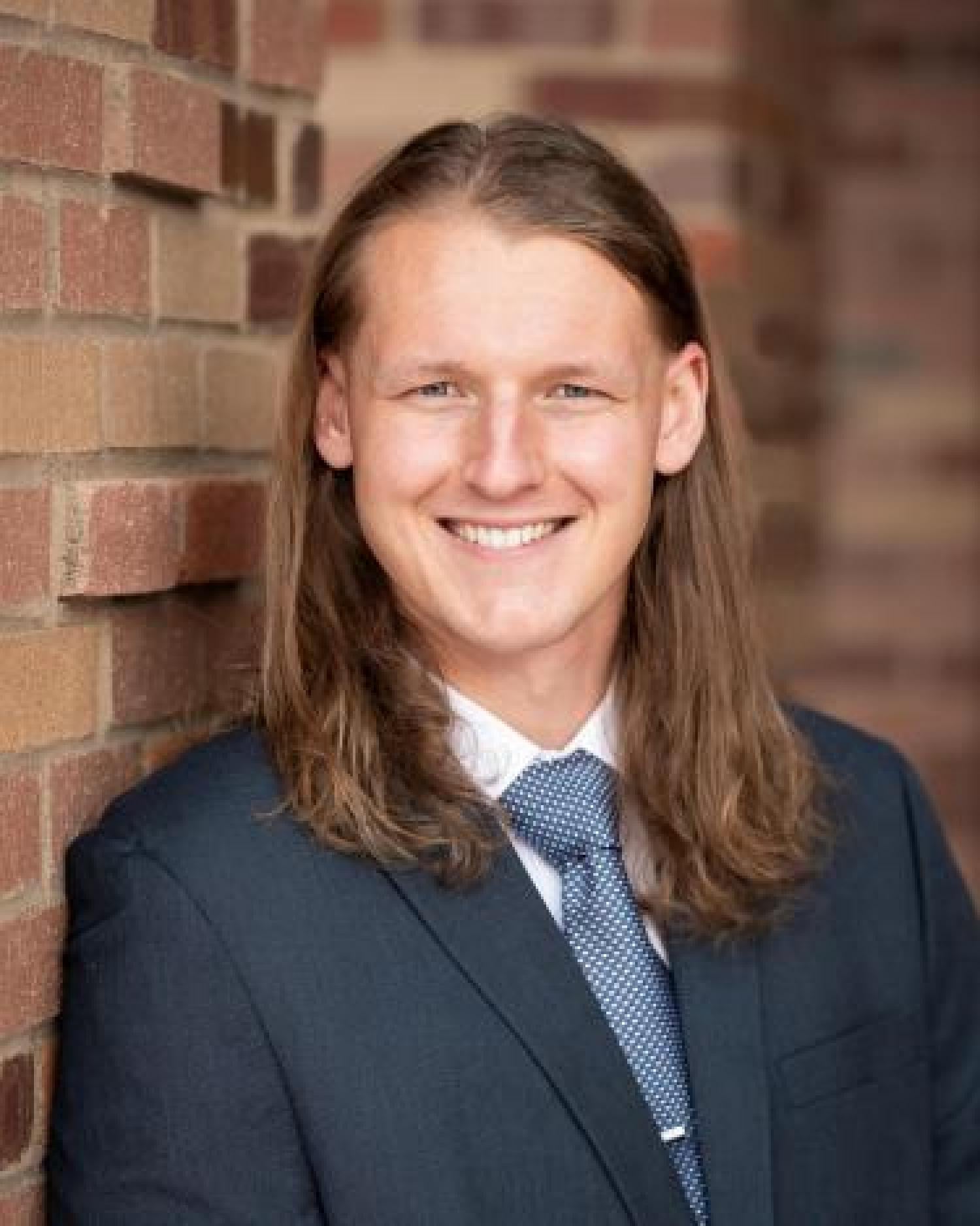 Todd Whittaker in suit in front of brick background