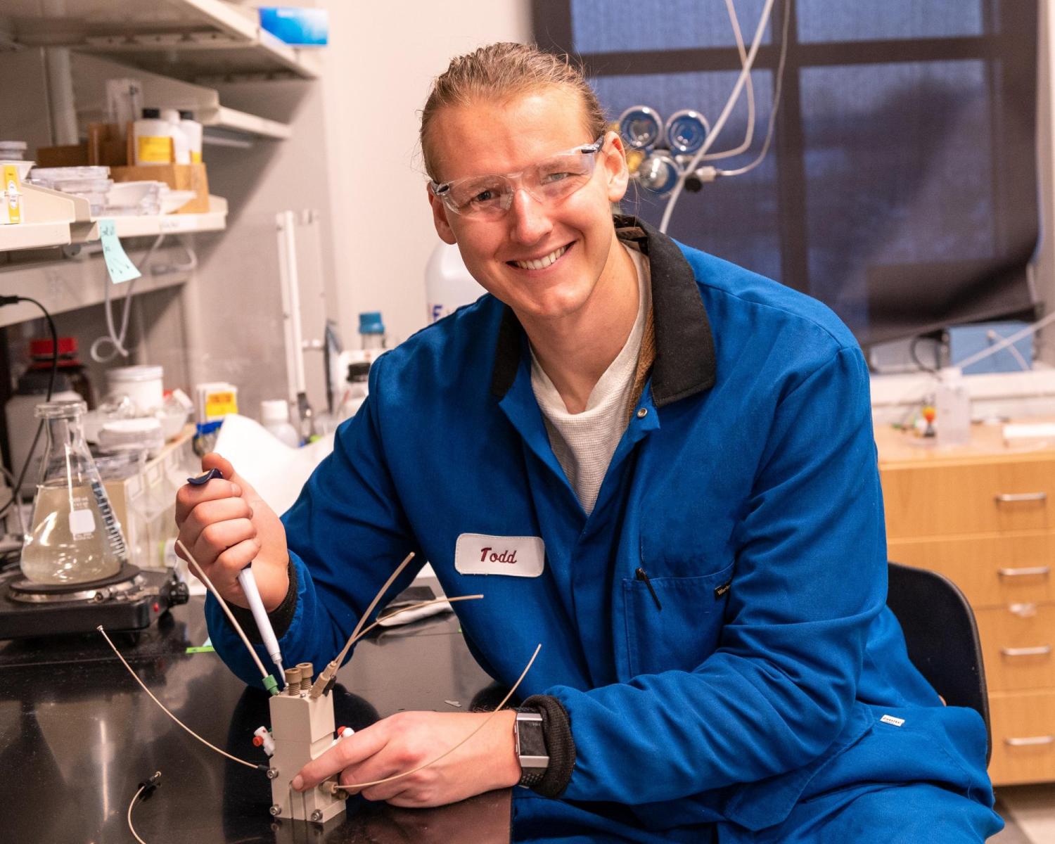 Todd Whittaker working at the bench in the lab with a blue jumpsuit on