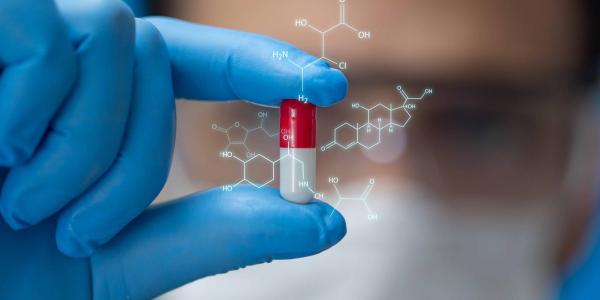 Scientist in lab holding a pill with chemical structure superimposed