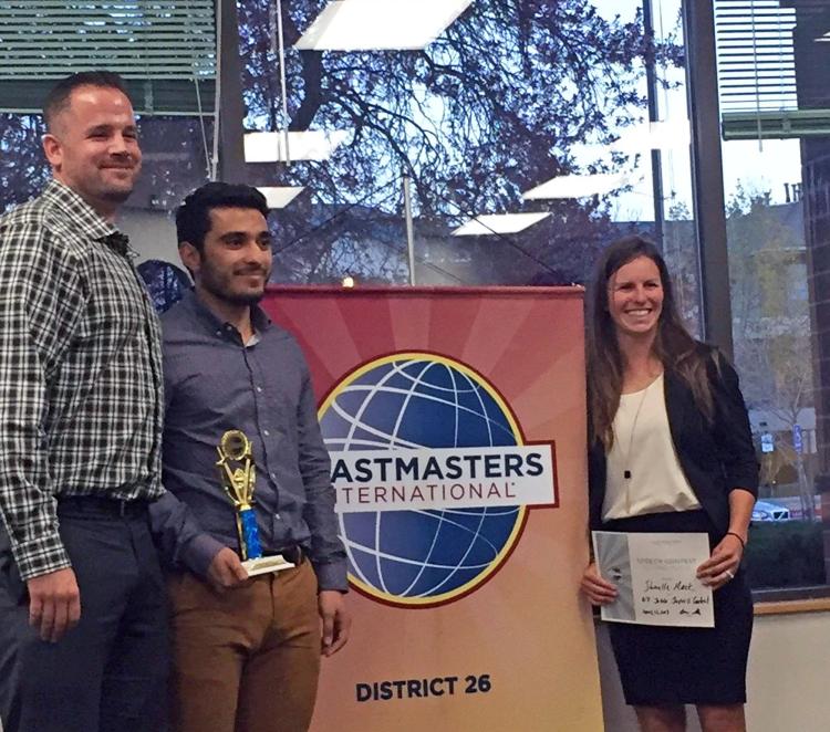 Hashim Al Hajji stands with Toastmasters International representatives with trophy.