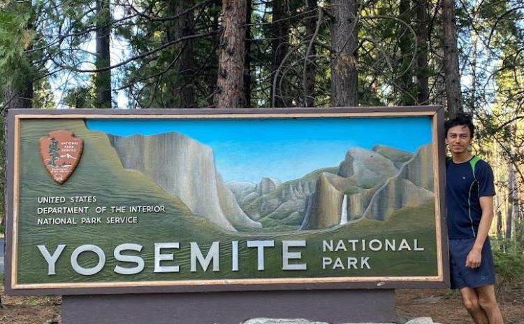 Barrientos stands by a Yosemite poster with trees in the background
