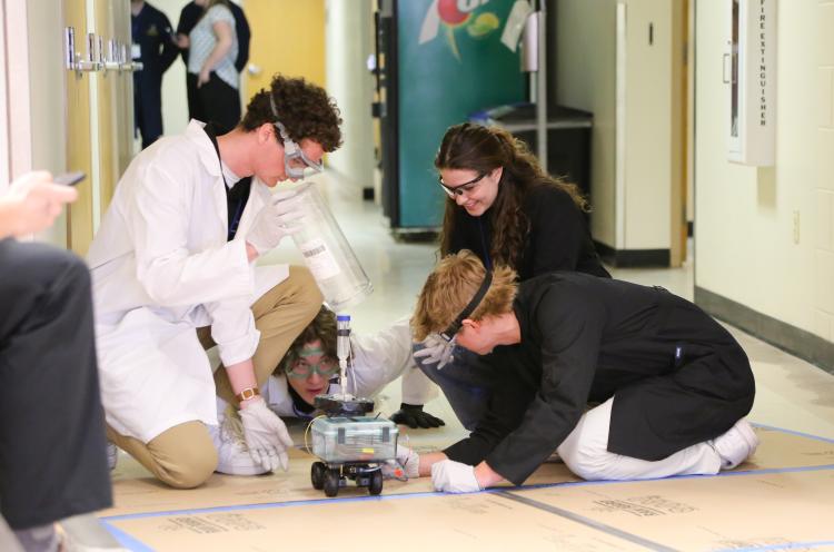 CU Boulder students bend over their car at the AIChE competition