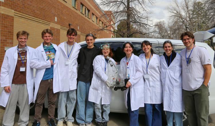 Ralphie team in white lab coats holding their car.