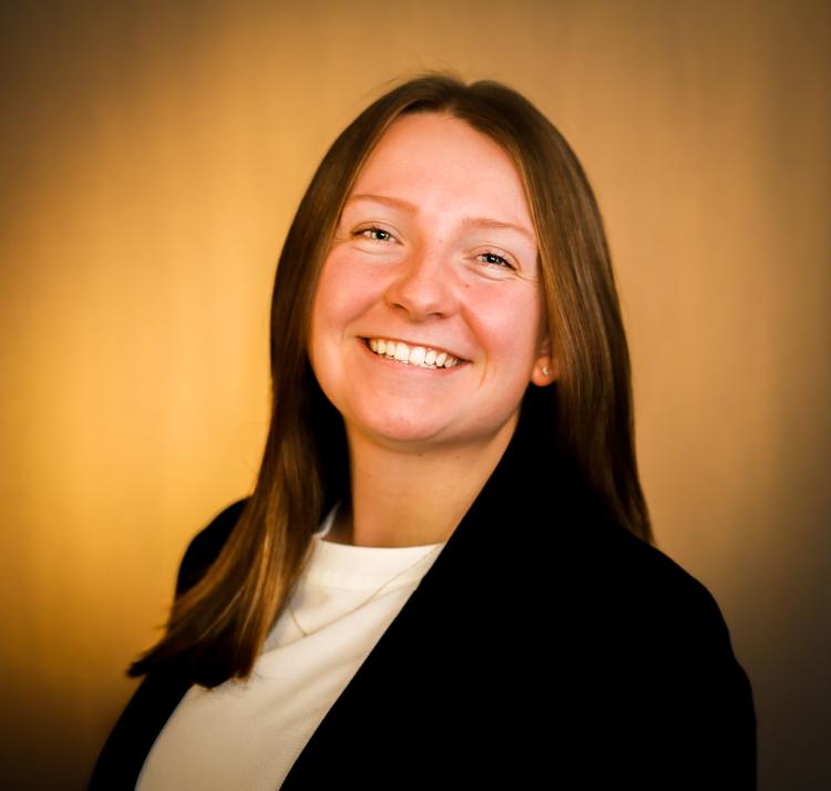 Delaney McNally in a dark blazer against a tan background