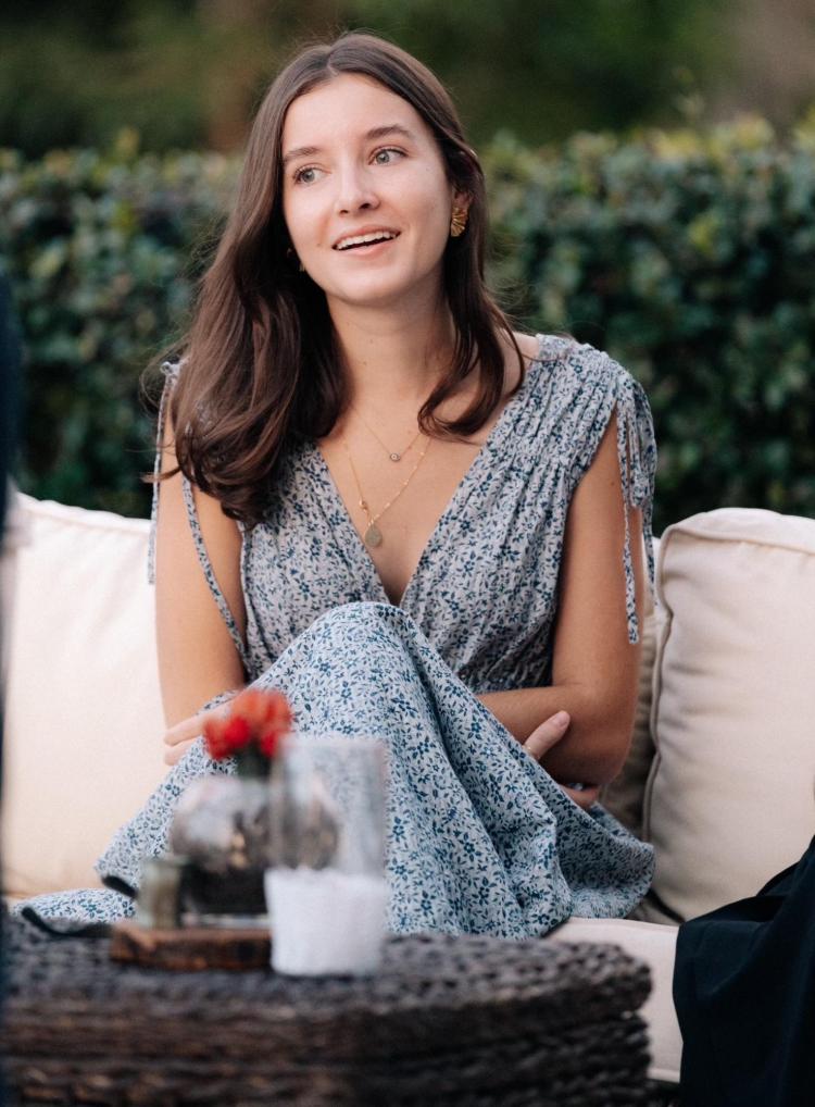 Hannah Padgette sitting outside on a coach in a summer dress.