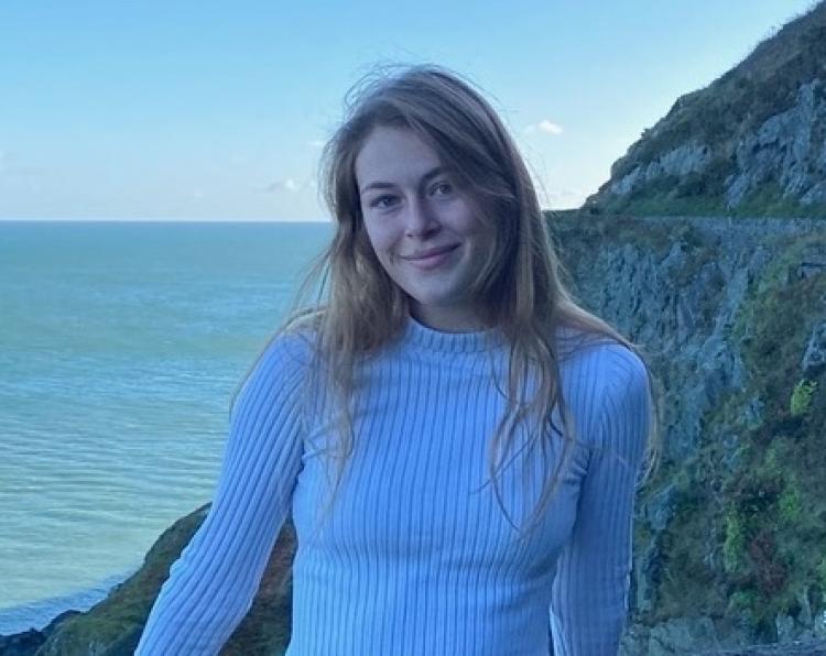 Wren Hoertdoerfer in front of a cliff by the ocean.