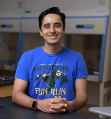 Saad Bhamla wearing a "Fun Run" T-shirt with hands clasped in front of him