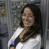 Katrina Knauer stands in a lab coat and is wearing plastic gloves
