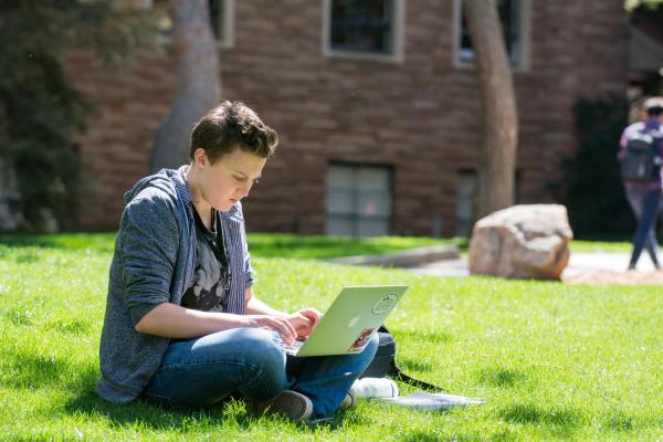 Student studying on a laptop outside on CU Boulder's Campus 