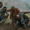 Actors Isiah Whitlock Jr, Norm Lewis, Clarke Peters, Delroy Lindo, and Jonathan Majors, playing Vietnam War veterans in "Da 5 Bloods." The actors are consoling each other on the ground in a forrest
