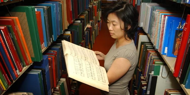 woman reading music book in library stacks