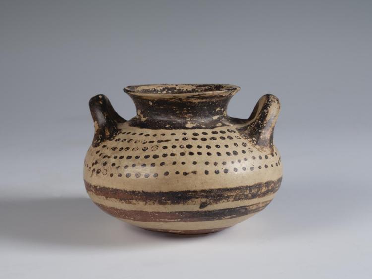 Photograph of squat jar, tan with brown slip decoration, from the side against a neutral gray background.