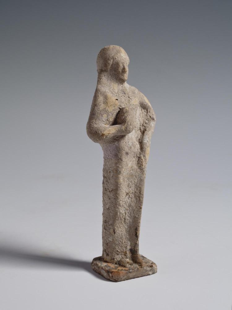 Photograph of terracotta female figurine, facing slightly to the viewer's right, against neutral gray background.
