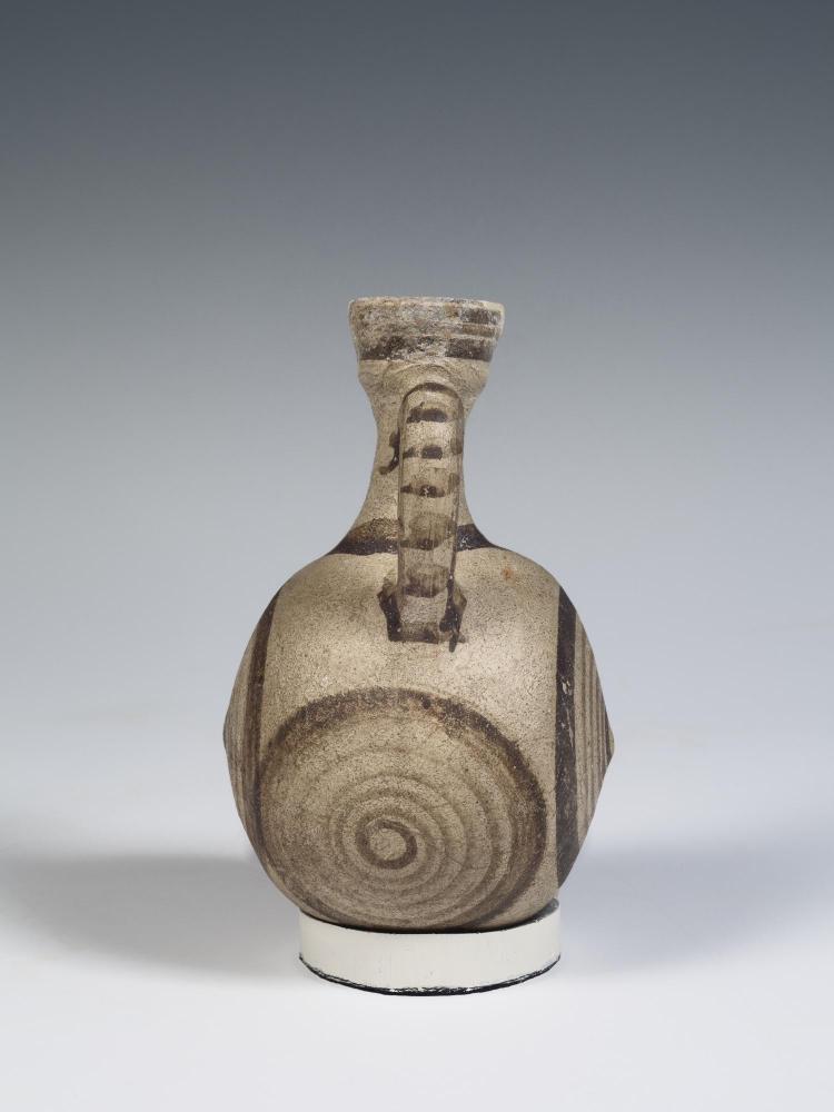 Photograph of a small, rounded jug from side, tan with brown decoration, against a neutral gray background.