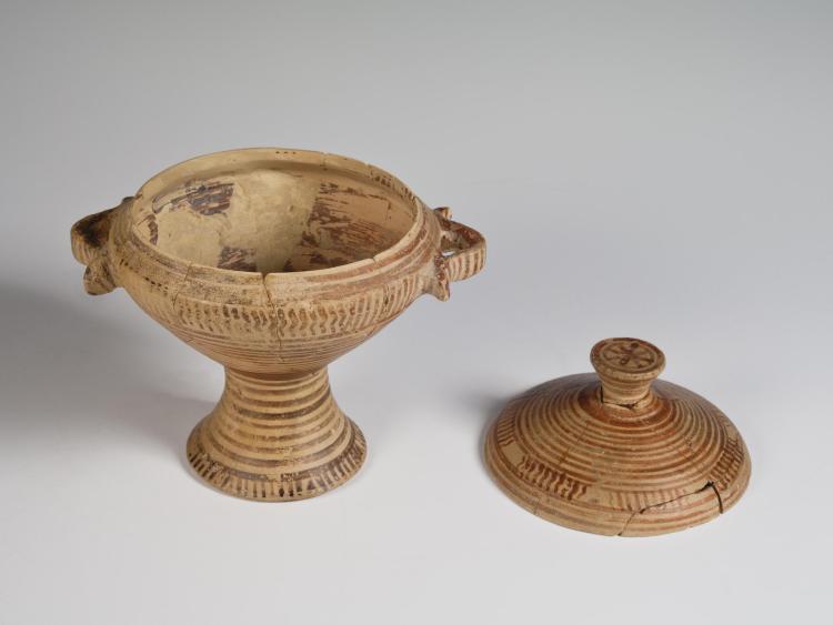 Photograph of pedestalled skyphos with lid removed and set next to it against a neutral gray background.
