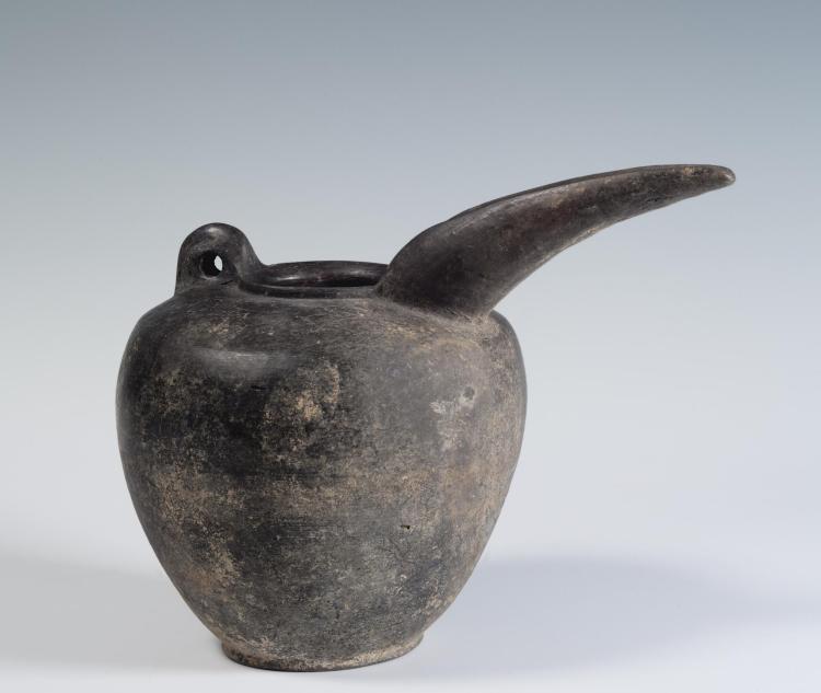 Photograph of a greyware beak-spouted jug, from the side against a neutral gray background.